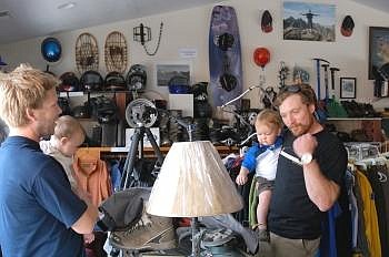 Karsten Carlson of Columbia Falls, holding his son Wyatt, 15 months, pumps his fist in excitement after selling sports items to All About Sports owner Michael Robison, who is with daughter Danicah, 8 months, in the Columbia Falls store on Monday. Allison Money photos/Daily Inter Lake