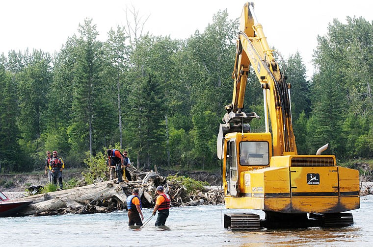 <p>Flathead County Road and Bridge and Flathead County Sheriff’s Department workers attach cables to debris in a logjam Tuesday afternoon in the Flathead River north of the Montana 35 bridge.</p>