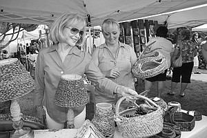 Harriet Cox, of Big Arm, admires original hand-made baskets created by Polson's Jo Phillips at the Sandpiper's Art in the Park event Saturday.