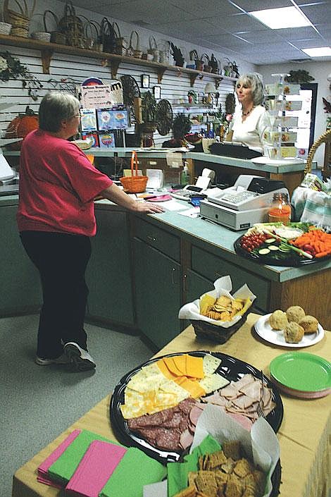 Jason Shueh/Valley Press Plains Garden Gift and Flower co-owner Patty Coe, left, talks with Lisa Larson at the grand opening of the flower and liquor shop. Throughout the day women received free roses and could snack on a variety of different refreshments.