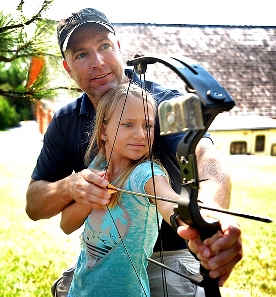 <p>Verlon Edwards of Somers teaches Mila, his 9-year-old daughter, how to use her first bow on Friday, August 10, in their back yard in Somers. Edwards is a long-time bow hunter and this year decided to agree to Mila's request for a bow of her own.</p>