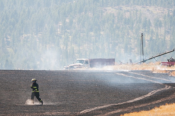 <p>Patrick Cote/Daily Inter Lake A firefighter walks through a burned field Tuesday afternoon at a grass fire off of Farm to Market Road west of Kalispell. Tuesday, Aug. 14, 2012 in Kalispell, Montana.</p>