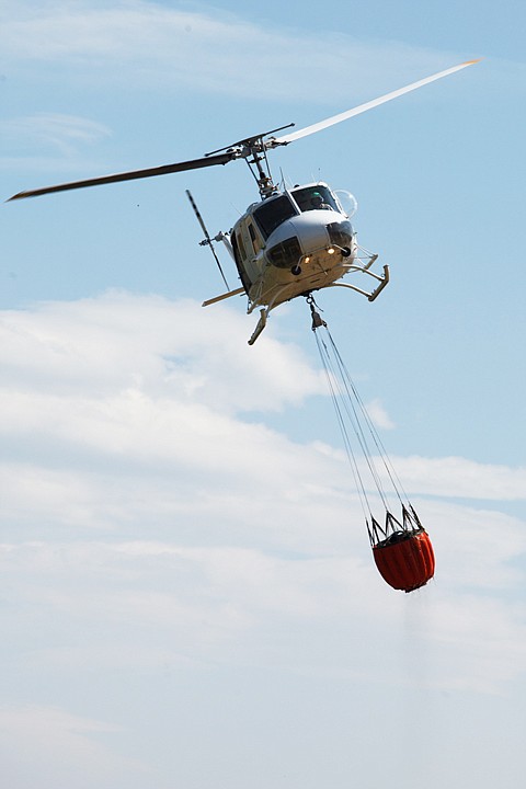 <p>Patrick Cote/Daily Inter Lake A Montana Department of Natural Resources and Conservation helicopter drops water Tuesday afternoon on a grass fire off of Farm to Market Road west of Kalispell. Tuesday, Aug. 14, 2012 in Kalispell, Montana.</p>