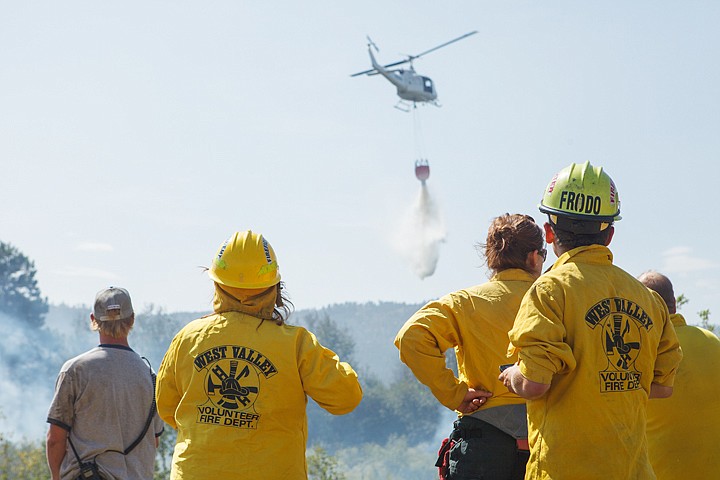 <p>Patrick Cote/Daily Inter Lake West Valley firefighters watch as a Montana Department of Natural Resources and Conservation helicopter drops water Tuesday afternoon on a grass fire off of Farm to Market Road west of Kalispell. Tuesday, Aug. 14, 2012 in Kalispell, Montana.</p>