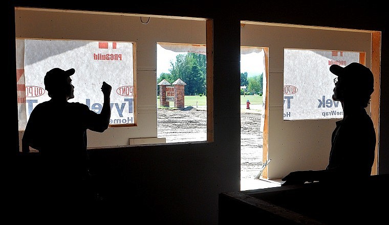 Tim Murry talks with his son, T.J. Murry, before putting up panels inside a new building that will house Western States Insurance Agency in the Village Plaza Business Park.