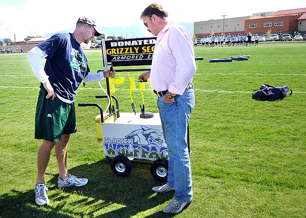 Glacier High School Football Coach Grady Bennett, left, takes a closer look at the new 20 gallon pressurized water tank donated by Greg Harris, right, of Grizzly Security Armored Express on Friday morning.