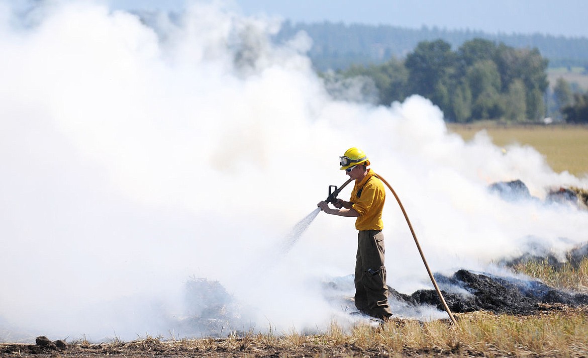 <p>Somers Volunteer Firefighter Everest George hoses down the perimeter of the fire after 700 hay bales caught fire on Lower Valley Road on Sunday.</p>