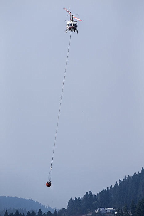 &lt;p&gt;A helicopter makes its way to the scene of a wildfire after scooping water from Rose Lake on Friday. The fire was burning in a heavily forested area near Fourth of July Pass.&lt;/p&gt;