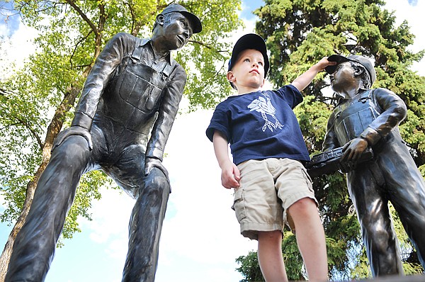 Jack Rickart, 5, of Laramie, Wyo., perches atop a statue in Depot Park as he surveys the crowd on Saturday at the 21st Annual Huckleberry Days Arts Festival in Whitefish.