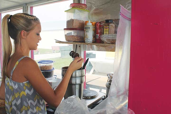 Brianna Carlile makes chocolate-covered strawberries at the Classy &amp; Crazy Cakes booth at the 2013 Grant County Fair. The booth's chocolate-covered strawberries, bananas and cheescakes are a big hit with fairgoers, she said.