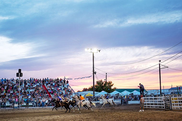 <p>Competitors race in the Indian Relay Races as the sun sets Thursday night during the second night of the Northwest Montana Fair Rodeo at the Flathead County Fairgrounds. Aug. 16, 2013 in Kalispell, Montana. (Patrick Cote/Daily Inter Lake)</p>