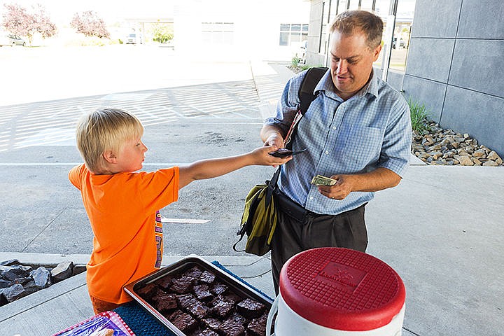 &lt;p&gt;Taylor Anderson, 8, hands a brownie to Food Services of America sales representative Frank Jones Friday at a lemonade and cookie stand at Timber Gastropub in Post Falls. Anderson is hosting the stand again today from 3 p.m. until 8 p.m. The proceeds will be split into thirds, benefitting a Coeur d&#146;Alene homeless shelter, a children&#146;s hospital and the remaining third funding a trip to Honduras to help build homes for the homeless.&lt;/p&gt;