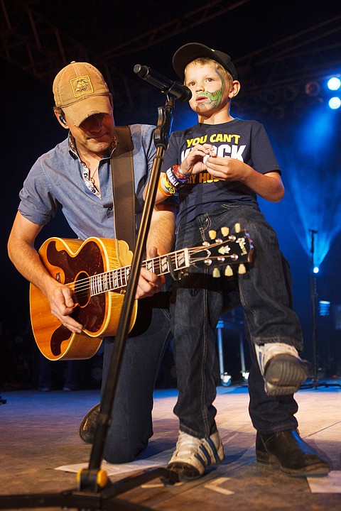 <p>Patrick Cote/Daily Inter Lake Rodney Atkins, left, brought Jayce Stickney, 6, up on stage to help sing a song Wednesday night during the Northwest Montana Fair at the Flathead County Fairgrounds. Wednesday, Aug. 15, 2012 in Kalispell, Montana.</p>