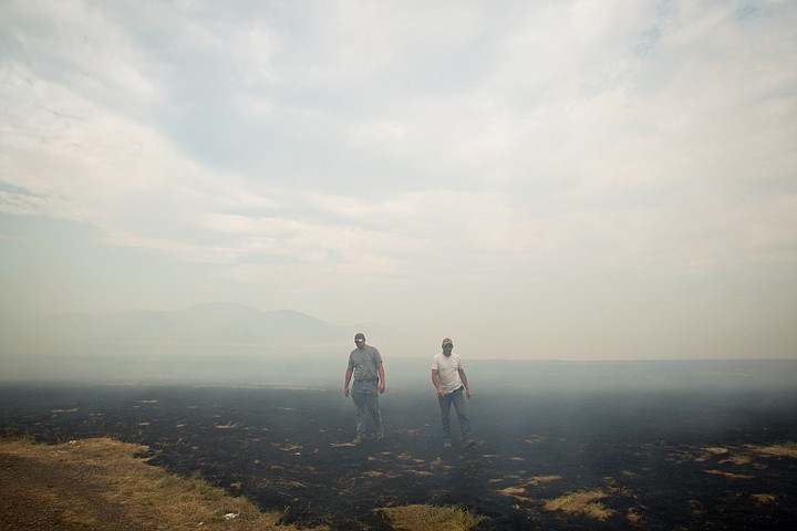 &lt;p&gt;Dustin Bedwell, left, and Lance Deacon, both with the Meyer farm, emerge from a smoldering bluegrass field on the Rathdrum Prairie Wednesday as 150 acres burned off after being harvested.&lt;/p&gt;