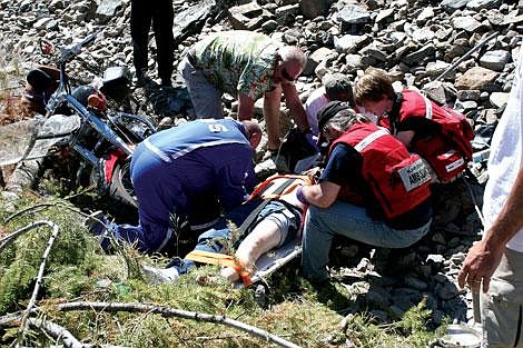 Jason Shueh/Valley Press Plains Ambulance crews strap motorcyclist Al Nicholson to a spine board and check the lacerations he received on his head.