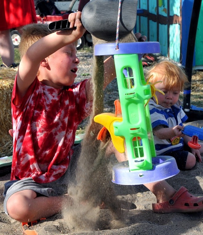 Elihu Shewalter, 5, dumps sand into a toy while his brother Elvi Shewalter, 1, plays next to him in a sandbox.