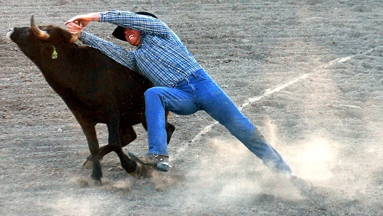 Keith Whitemarsh of Pasco, WA keeps a grip on one of his steer's horses while trying to bring the animal to the ground during Steer Wrestling.