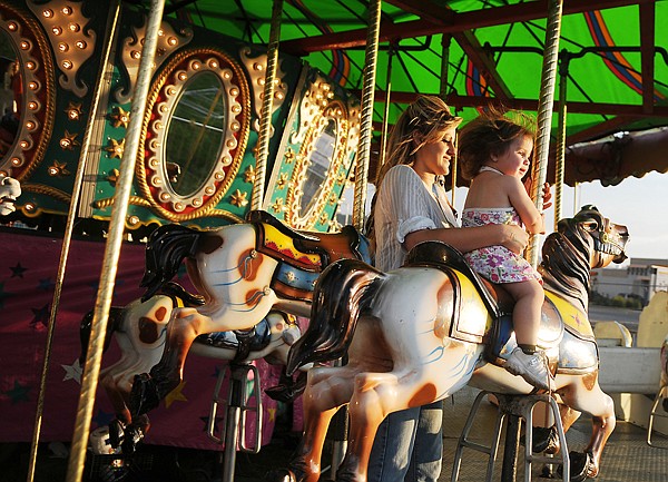 Chlsea Cross of Kalispell and her daughter Nevaeah Hernandez, 16 months, enjoy a ride on the merry-go-round on Wednesday at the Northwest Montana Fair.