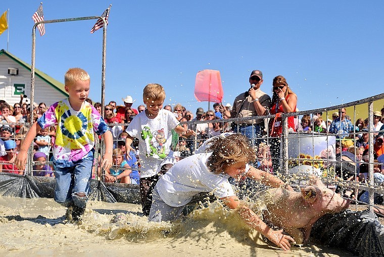 Abigail Fisher, 7, dives toward a small hog as Tyler Stronse, 6 (left), and Dawson Olsen, 5, try to come to their teammates aid during pig wrestling at the Northwest Montana Fair Friday afternoon.