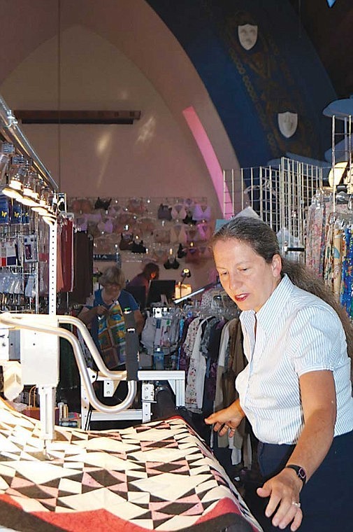 PJ Jacobsen, of Crazy Quilter, demonstrates how her quilting machine works. Her business is inside the former Methodist Church in Lind. She and her husband bought the church on eBay.