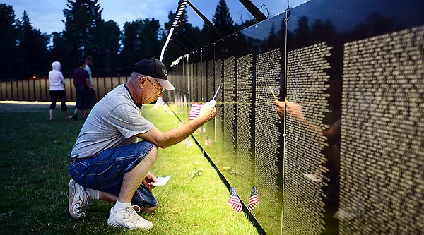 <p>Lloyd Hanson of Columbia Falls searches for the name of Michael Peterson, a friend from high school, on Thursday, August 22, at The Moving Wall Vietnam Veterans Memorial in Whitefish. Hanson planted a flag when he found Peterson's name. (Brenda Ahearn/Daily Inter Lake)</p>