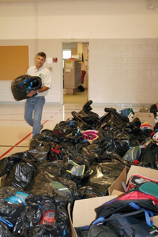 Rotary Club member Bob Tatum adds a bag of backpacks filled with
school supplies to the pile at Larson Heights Elementary School as
part of the club's "Backpacks for Kids" event.