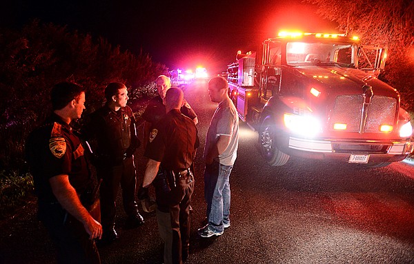 <p>Flathead County sheriff’s deputies gather near fire trucks on Trumble Creek Road Tuesday night after a man was arrested for allegedly starting a home on fire.</p>