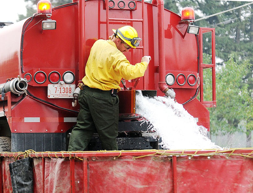 &lt;p&gt;&lt;strong&gt;A firefighter&lt;/strong&gt; fills up a portable holding pond with water at the grassfire in Evergreen on Friday. (Aaric Bryan/Daily Inter Lake)&lt;/p&gt;
