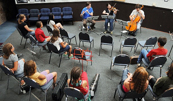 Visiting Juilliard students Shawn Wyckoff, flute, left to right, Maria Millar, violin, and Adrian Daurov, cello, play a few songs for music students gathered at the Discovery Center on Thursday in Columbia Falls.