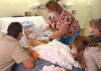 GRANDMA DONNA, sister Danielle, 11, and dad DJ watch Kiley, 6, (clockwise from right) as Randi Cogburn, Kiley's nurse at the KRMC Outpatient Infusion, locates the mediport in her chest before sterilizing the area to draw blood prior to treatment Wednesday morning. Allison Money/Daily Inter Lake