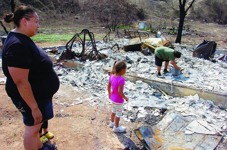 <p>LuAnna Fox and her 3-year-old daughter Kamille watch her 10-year-old son Sheldon look for salvageable items from the ruins of the family’s house on the Northern Cheyenne Indian Reservation in this Aug. 9 photograph.</p>