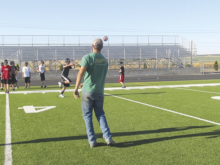 Royal assistant coach Kyle Scroggins tosses the ball to freshman
newcomer Aaron Johnson during a session for receivers.