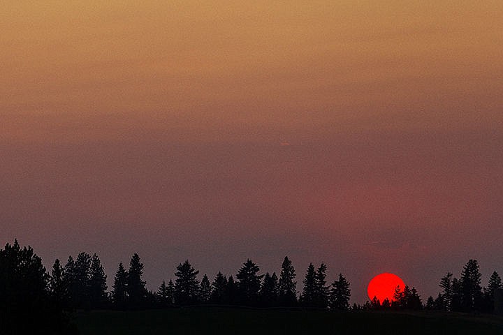 &lt;p&gt;SHAWN GUST/Press&lt;/p&gt;&lt;p&gt;The sun appears as a giant red disk as it sets behind a stand of trees Monday in Coeur d&#146;Alene.&lt;/p&gt;