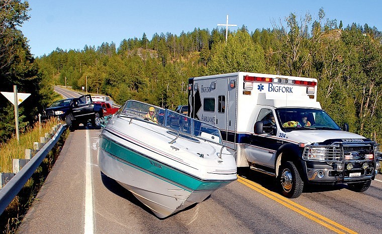 An ambulance heads past a boat that came loose from a pickup truck during a collision at the Montana 82 bridge over the Flathead River on Friday evening.