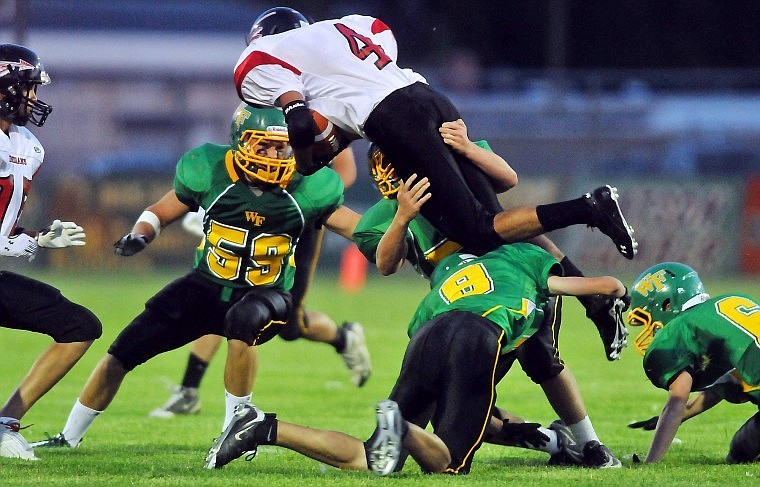 Whitefish's Robby Neff (59) and Logan Harwood (9) get their hands on Browning's Brendon Runningwolf to tackle him in the air during Friday night's game in Whitefish.
