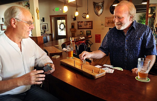 TurboCrib creators Don Robinson, left, and Keith Bassett demonstrate how to play the game on Thursday at the Cottage Inn in Kila.