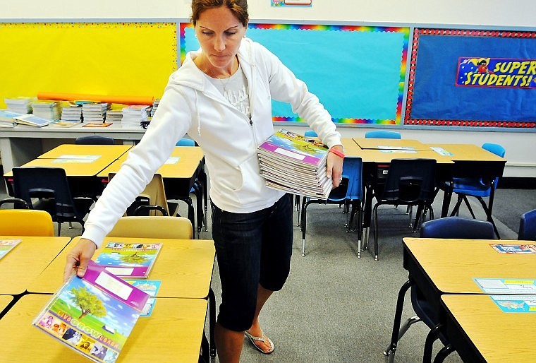 First-year West Valley School teacher Kimberly Buls sets calendars on her students' desks Tuesday afternoon while preparing for the first day of school today. The school expects an additional 38 students, which contributed to Buls being hired to teach fourth grade only two weeks ago.