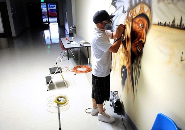 Ely Yerian, 23, of Columbia Falls works on the Home of the Chiefs mural on Wednesday at Helena Flats School. Yerian, a former student, began the project on a volunteer basis, an anonymous benefactor liked the work to the extent that it became a paying job for Yerian and was expanded to two murals.