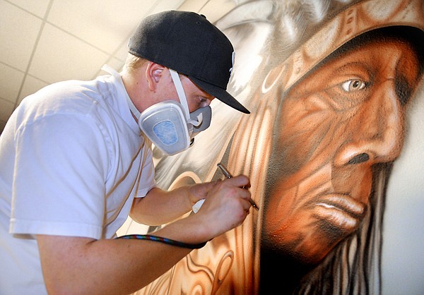 Ely Yerian, 23, of Columbia Falls works on the Home of the Chiefs mural on Wednesday at Helena Flats School. Yerian, a former student, began the project on a volunteer basis, an anonymous benefactor liked the work to the extent that it became a paying job for Yerian and was expanded to two murals.