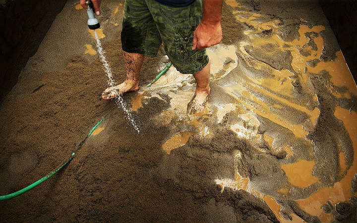 &lt;p&gt;Scott Dodson, of Coeur d'Alene, waters down sand donated from Central Pre-Mix for a sandcastle, Wednesday, before this weekend's Art on The Green at North Idaho College. This is Dodson's seventeenth year at Art on The Green carving a castle, totaling around 16 tons of sand.&lt;/p&gt;