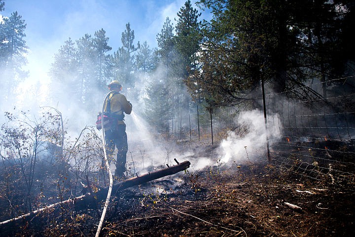 &lt;p&gt;Northern Lakes firefighter Tyler Denham douses hot spots at a roughly on-acre fire on Monday behind a private residence alongside Highway 53 near Greensferry Road.&lt;/p&gt;