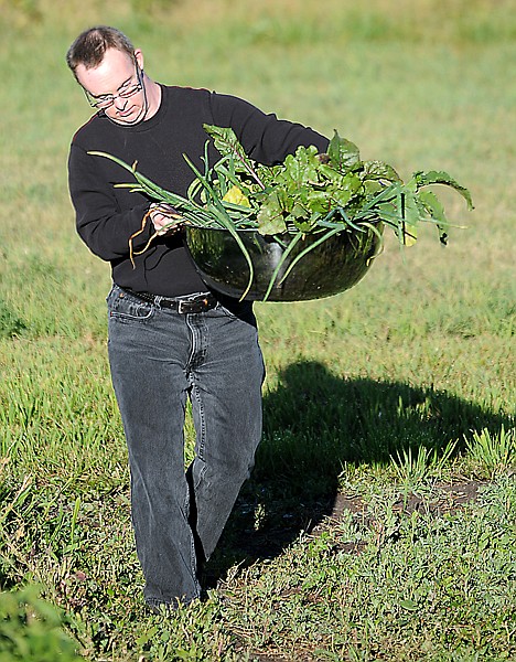 <p>Nathan Bunyan brings onions and other greens from the garden on Wednesday morning, September 5, at the Lighthouse Christian Home.</p>