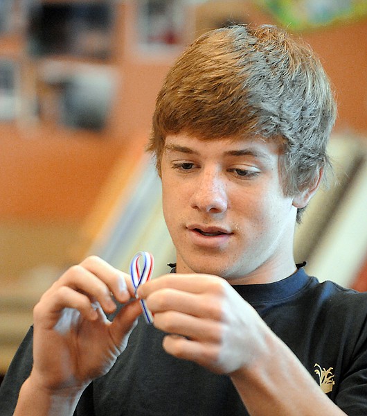 <p>Grant Tafoya, a junior in Kristyn Morin's class, helps make red,
white and blue memorial ribbons on Wednesday morning at Glacier
High School.</p>