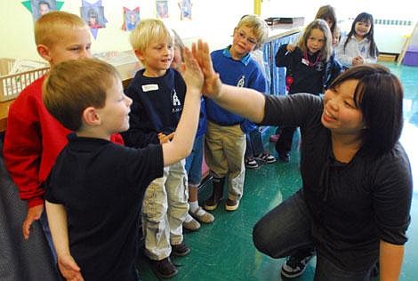 Yukie Yoneda, 20, of St. Thomas University in Osaka, Japan, high-fives St. Matthew&#146;s School kindergartner Zachary Lapke at the school Tuesday. Yoneda is visiting several area schools along with colleagues from St. Thomas. The group is here on a cultural exchange trip with other stops including Glacier High School, Montessori, Salish-Kootenai College and an Amish community near Eureka. Garrett Cheen/Daily Inter Lake