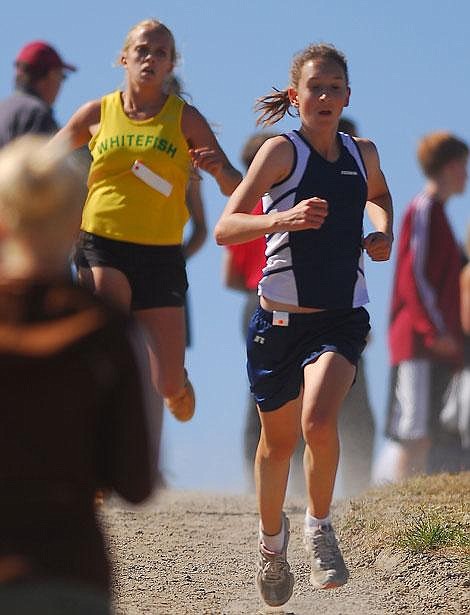 Glacier High School&#146;s Heather Fraley races downhill ahead of Whitefish&#146;s Loni Hanson during the Flathead Invitational cross country meet Saturday at Kidsports Complex. Fraley finished fourth with a time of 19:46, and Hanson took sixth with a time of 20:01. Garrett Cheen/Daily Inter Lake