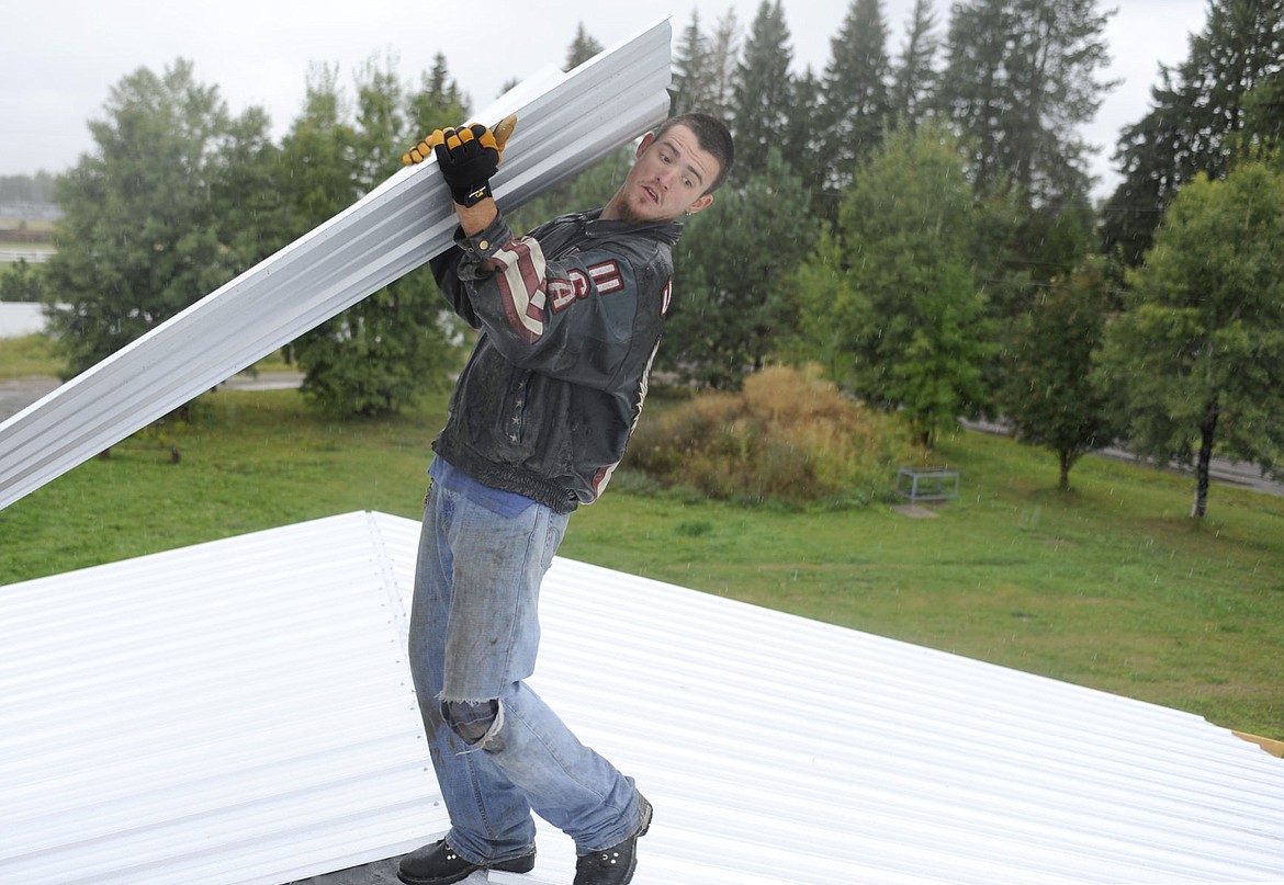 <p>Mike West puts a metal sheet in place for Alfreda Pilond's mobile home roof in Columbia Falls on Wednesday. (Aaric Bryan/Daily Inter Lake)</p>