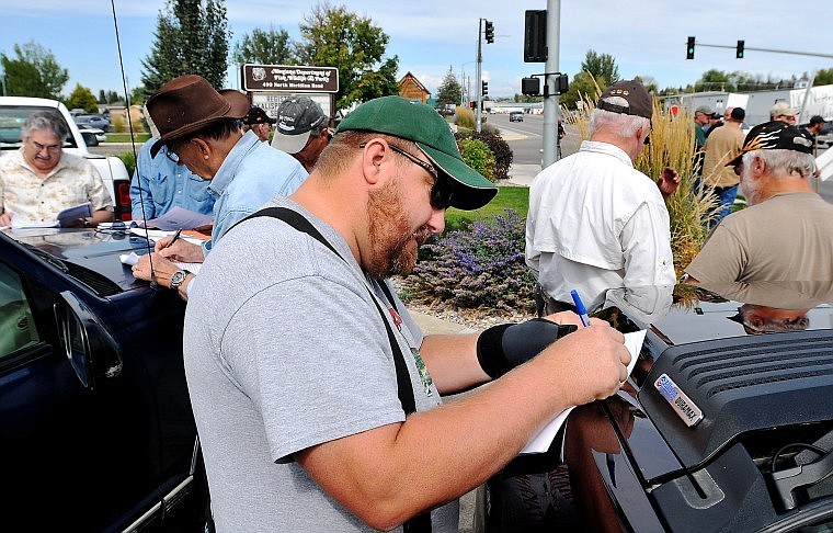 Peter Jellar signs a contact list form for &quot;Citizens Against Co-Management and Netting of Flathead Lake&quot; while others at the demonstration do the same.