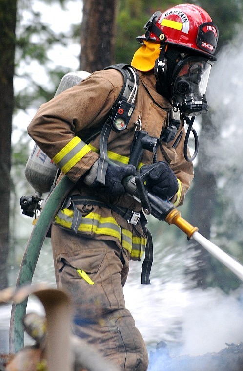 A firefighter sprays a water hose onto the fire.