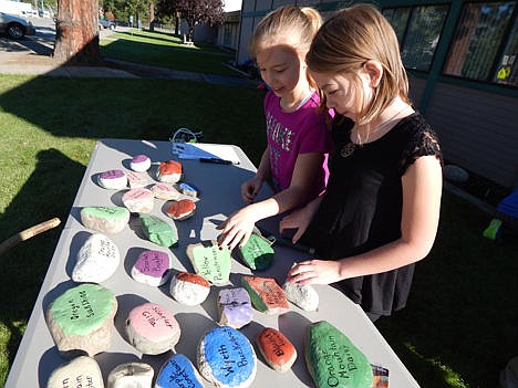 &lt;p&gt;Julia Spaulding and Olivia Carrel, John Brown Elementary School students, look at rocks with plant names painted on them during a school-wide planting event Friday.&lt;/p&gt;