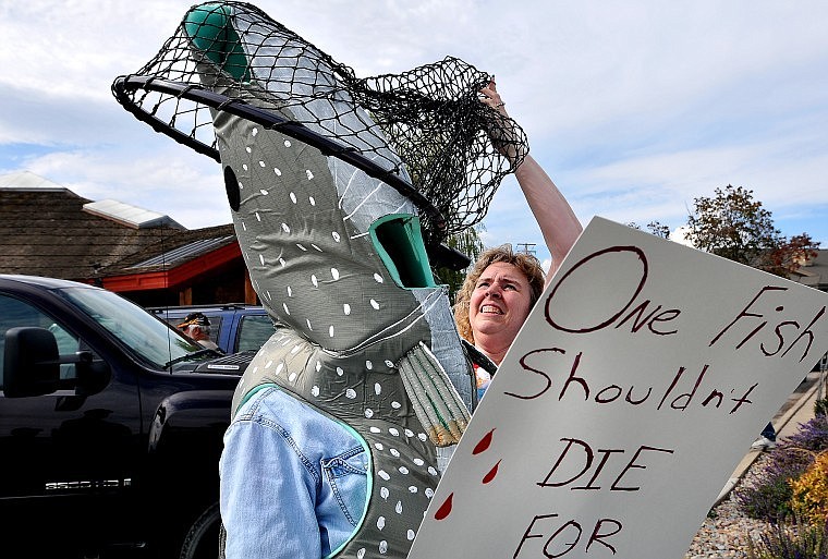 Gail Shattuck puts a net over her husband, Tim, a guide for Flathead Lake Charters who dressed in a fish costume during a protest outside the Montana Fish, Wildlife and Parks office in Kalispell on Tuesday afternoon. The group opposes proposals to target lake trout in Flathead Lake with extensive netting. The Confederated Salish and Kootenai Tribes are preparing an environmental review that will outline those plans.